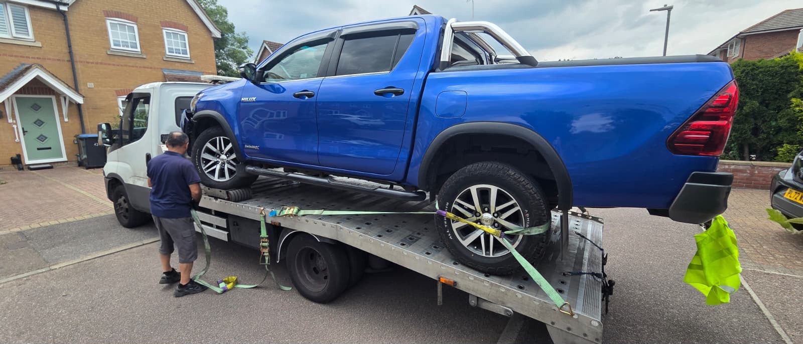 Blue pickup truck secured on a flatbed recovery vehicle