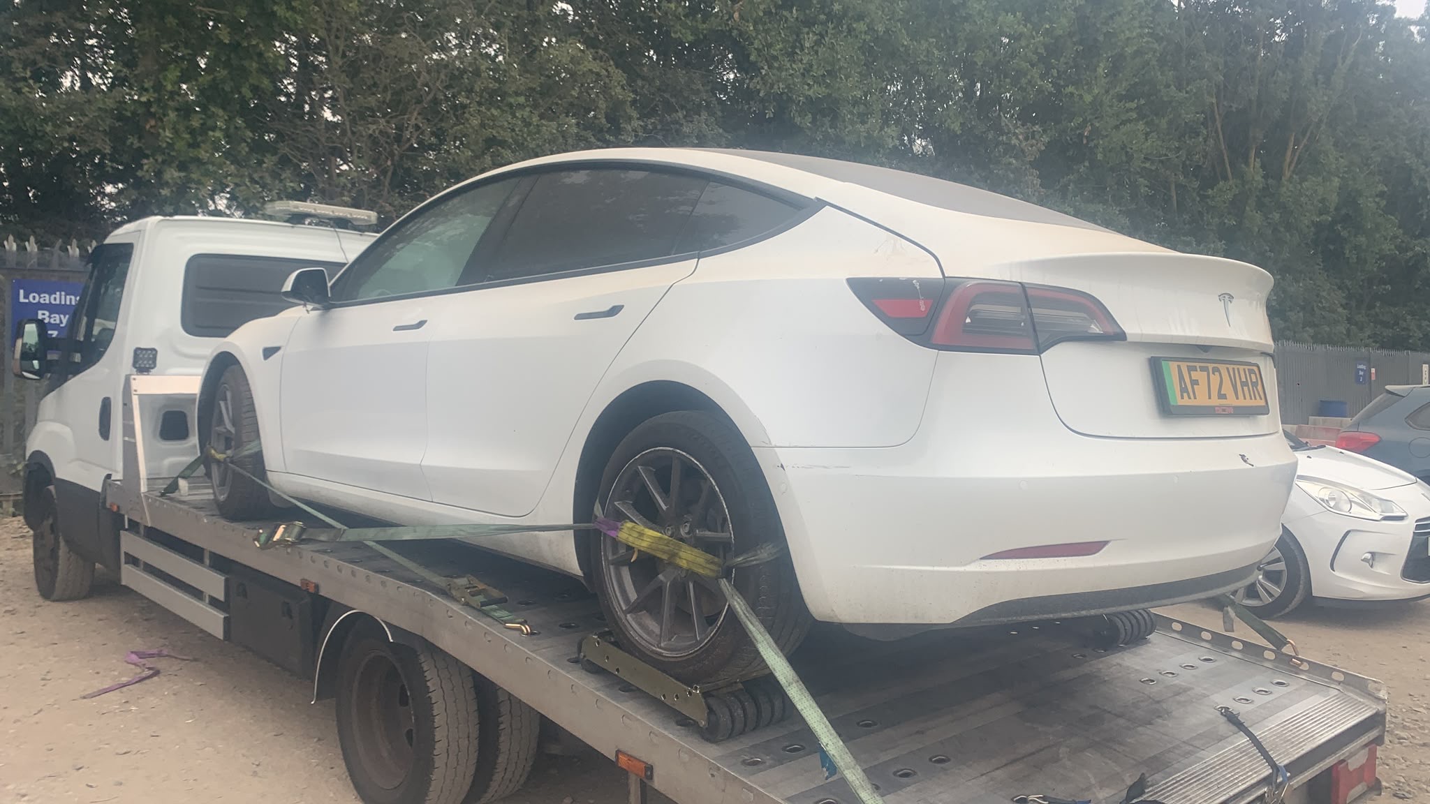 White Tesla secured on a flatbed recovery truck